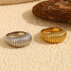 Detailed view of gold and silver retro ribbed rings on a textured ivory surface