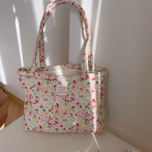 Detail of pink floral quilted cotton tote bag with white woven label and soft texture