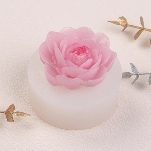 Macro shot of 3D peony silicone mold with a finished pink candle and golden accents