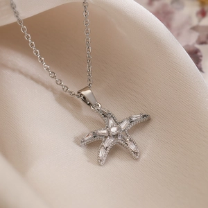 Elegant silver starfish pendant necklace with cubic zirconia on beige satin background