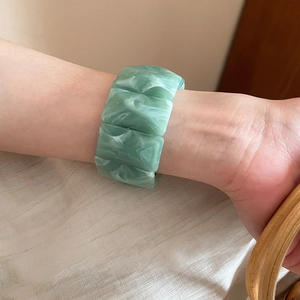 Close-up of green marble pattern acrylic stretch bracelet on woman's wrist