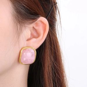 Gros plan détaillé d'une boucle d'oreille en résine rose avec bordure dorée