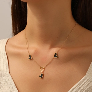Collana minimalista in acciaio inossidabile dorato con ciondoli a cuore nero su modella