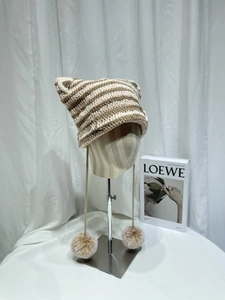 Detail view of brown and white striped knit cat ear hat with pom-poms and silver pins