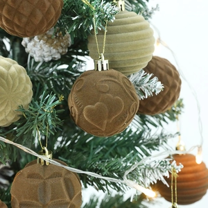 Close-up of velvet Christmas balls with heart patterns hanging on a snowy tree branch