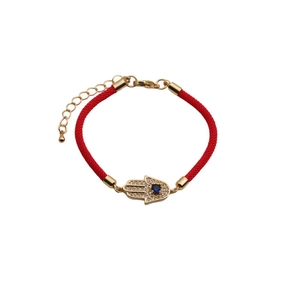 Detailed view of red woven cord bracelet featuring a gold Hamsa hand and blue zircon