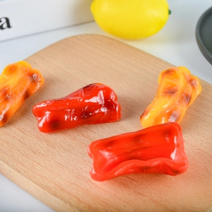 Realistic artificial grilled bell pepper models in red and yellow on a wooden board