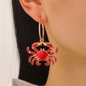 Detail of red crab drop earring with gold hoop on model showing beach ocean style