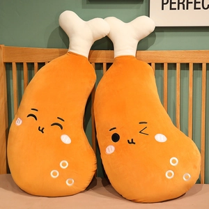 Detailed view of two cute cartoon fried chicken leg plush pillows resting on a wooden bed