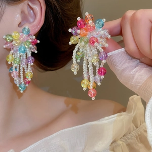 Détail de boucles d'oreilles à pompons perlés colorés avec perles sur un mannequin