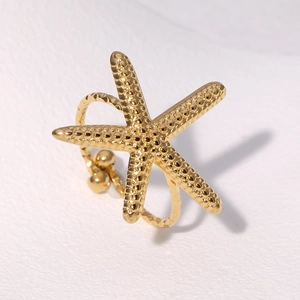 Close-up of a minimalist gold starfish ring featuring detailed beaded texture and metallic finish