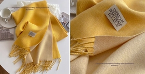 Detail of a ginger and beige cashmere-feel scarf showing fine fringe and soft texture