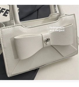Close-up of white PU leather bag featuring a large bow and heart-shaped rhinestone detail