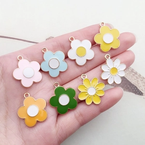 Detail view of colorful enamel flower charms for DIY jewelry making held in hand