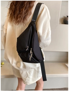 Side view of black crossbody chest bag with adjustable wide strap shown on model