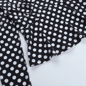 Dettaglio del tessuto nero a pois bianchi con orlo liscio e trama a maglia fine