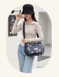 Detailed view of women's floral crossbody bag with multiple zippers and adjustable strap