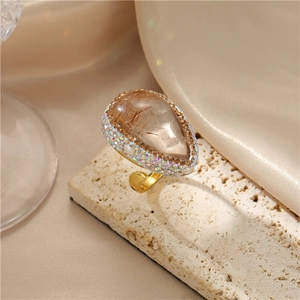 Dettaglio macro dell'anello barocco dorato a goccia con pietra di cristallo e diamanti