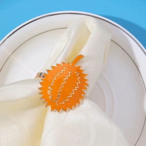 Detailed view of an orange durian-shaped metal napkin ring on a beige napkin