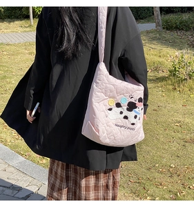 Detail of pink quilted tote bag with naughty puppy embroidery and adjustable shoulder strap