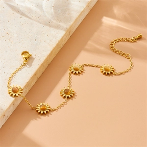 Detail of gold floral bracelet with amber sunflower charms and lobster clasp on marble stone
