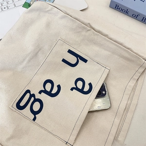 Close-up of canvas tote bag front pocket with haag logo showing smartphone storage utility