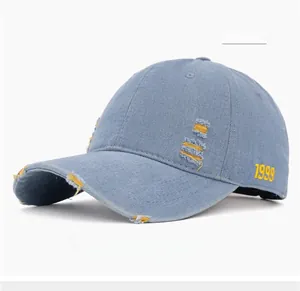 Detail of light blue distressed denim baseball cap with 1999 embroidery and yellow patches