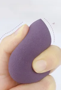 Close-up of a purple teardrop makeup sponge being squeezed to show soft high elasticity