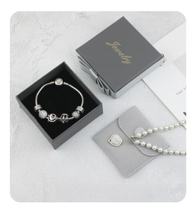 Detail of dark grey rectangular jewelry box with snap velvet pouch and pearl necklace