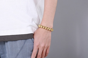 Close-up of man wearing a golden bicycle chain style bracelet in titanium steel