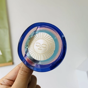 Macro view of sun-embossed highlighter powder in a blue translucent iridescent case