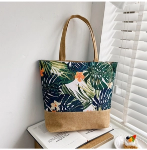 Detail of tropical plant print canvas tote bag with jute base on a book background