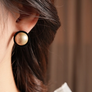 Close-up of vintage round earrings with gold center and black velvet-textured trim