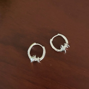 Detail showing twisted texture 925 sterling silver earrings on a dark wood surface