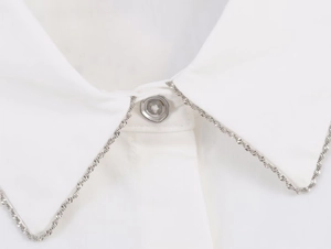 Detailed view of white poplin shirt collar featuring silver chain trim and clear resin buttons