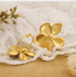 Detailed close-up of golden metal floral earrings on vintage lace and linen fabric