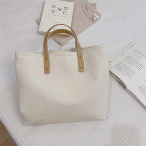 Detailed shot of beige cotton tote bag with vertical stripes and leather rivet handles