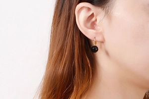 Detail of 10mm faceted black crystal bead drop earring on model with gold hook