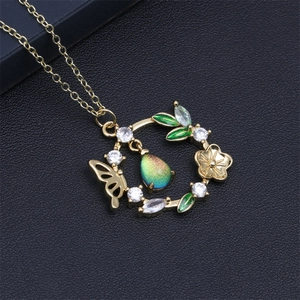 Détail du pendentif couronne de fleurs et papillon doré avec pierre arc-en-ciel