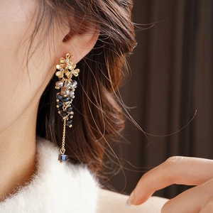 Detailed shot of golden flower tassel earrings with black beads and blue pendant