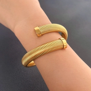 Detail of a golden Tubogas spiral bracelet showing its ribbed texture and elastic design