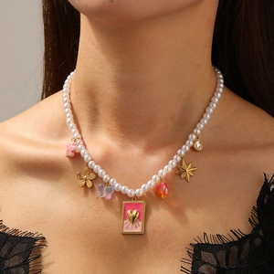 Gold pearl necklace with pink gradient heart pendant and star charms on a model