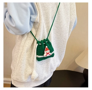 Detail view of handmade crochet mini bag with snowman decor and white drawstring pom-poms