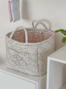 Detail eines geblümten gesteppten Aufbewahrungskorbs mit Griffen und vorderer Tasche