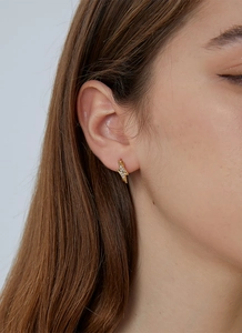 Close-up of gold lightning bolt earrings with pavé zircons on model ear