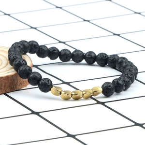Lava stone bead bracelet with irregular gold accents on a natural wood display