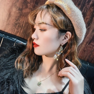 Close-up of model wearing hollow teardrop earrings with multi-colored crystals and tassels