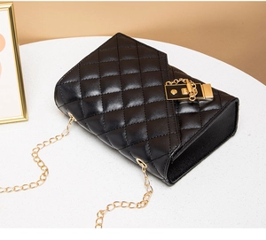 Close-up of black quilted small square bag featuring a gold chain and metal lock buckle