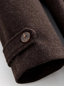 Detailed close-up of dark brown wool coat cuff with matching button and strap texture