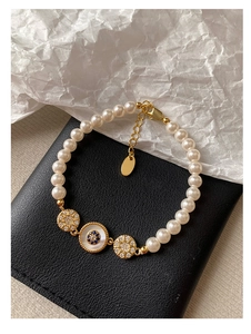 Détail du bracelet de perles plaqué or 18k avec zircon et breloque en émail bleu